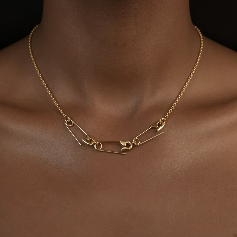 Gold chain necklace with three linked safety pins, worn around a model’s neck - 24jewels