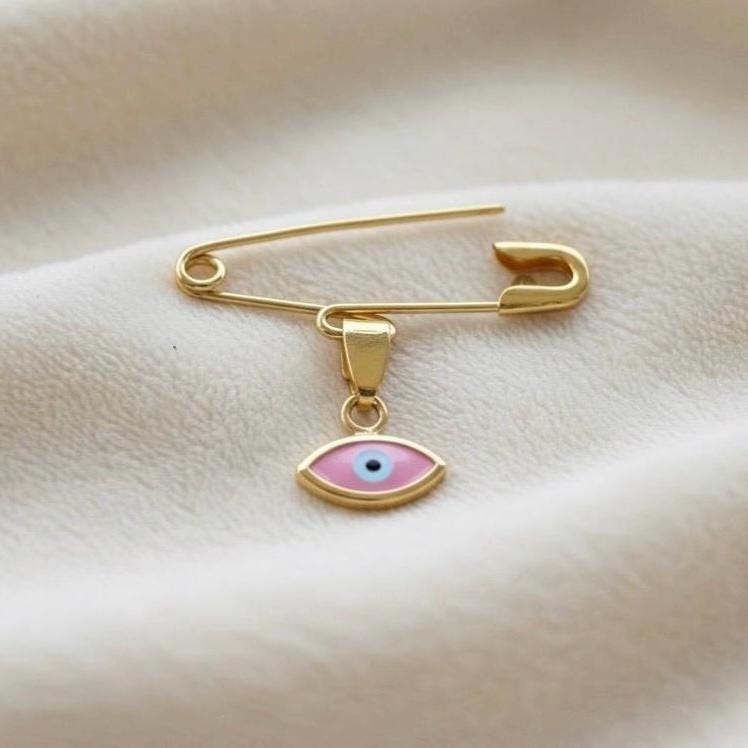 14K Gold Baptism Baby Pin Pink Evil Eye Brooch on smooth surface