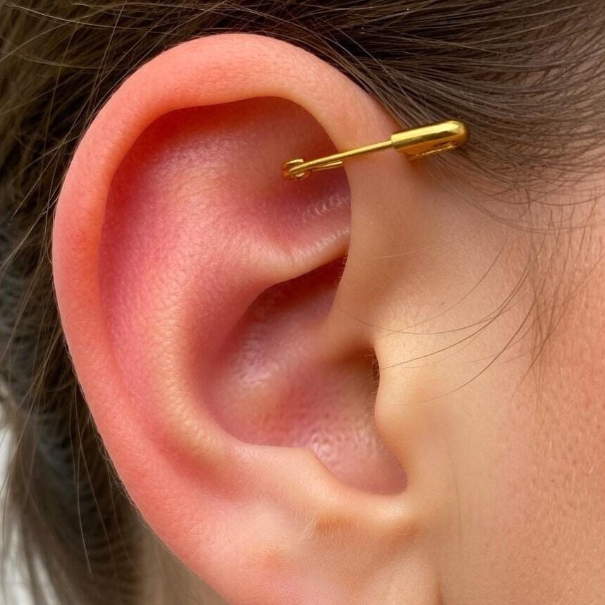 Yellow gold plated safety pin mini earring worn on upper ear cartilage.
