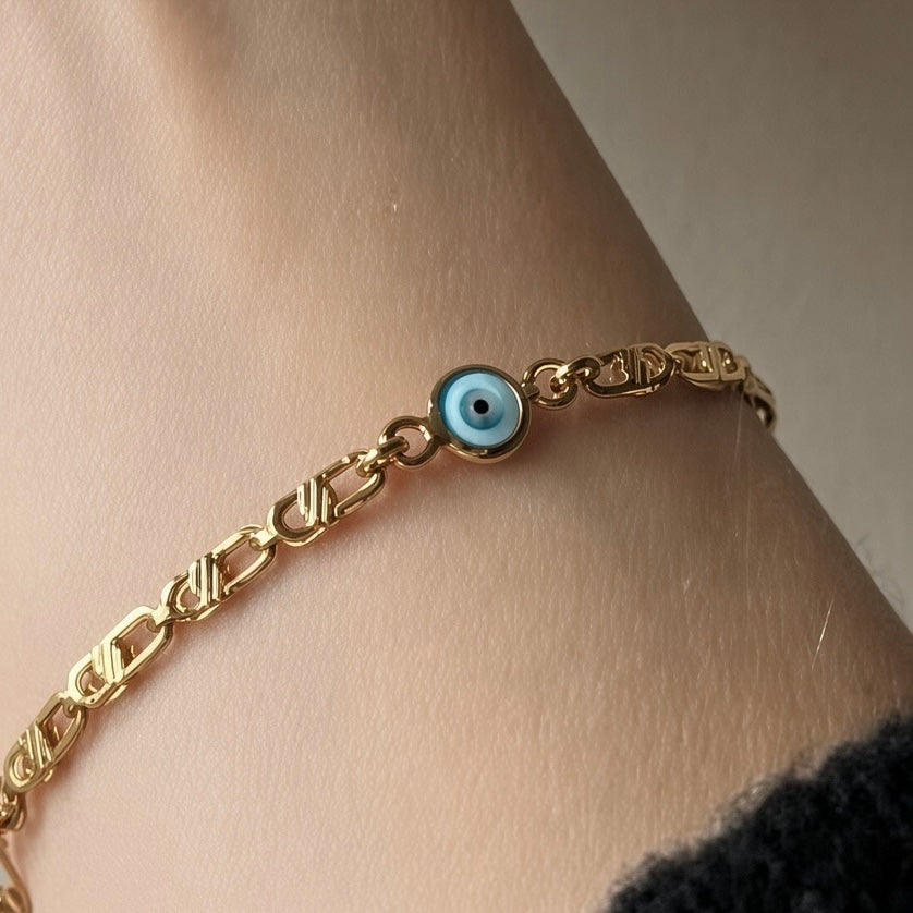 Delicate gold baby bracelet with a blue evil eye charm and small heart detail.