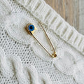 Gold Evil Eye Safety Pin Brooch – Nazar Protection Jewellery on white woolen fabric - 24jewels