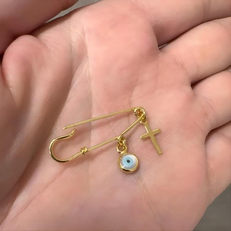 Gold Evil Eye Safety Pin Cross Brooch 1.25” held in a palm - 24jewels