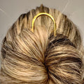Yellow gold U-shaped French hair pin securing a twisted bun hairstyle.