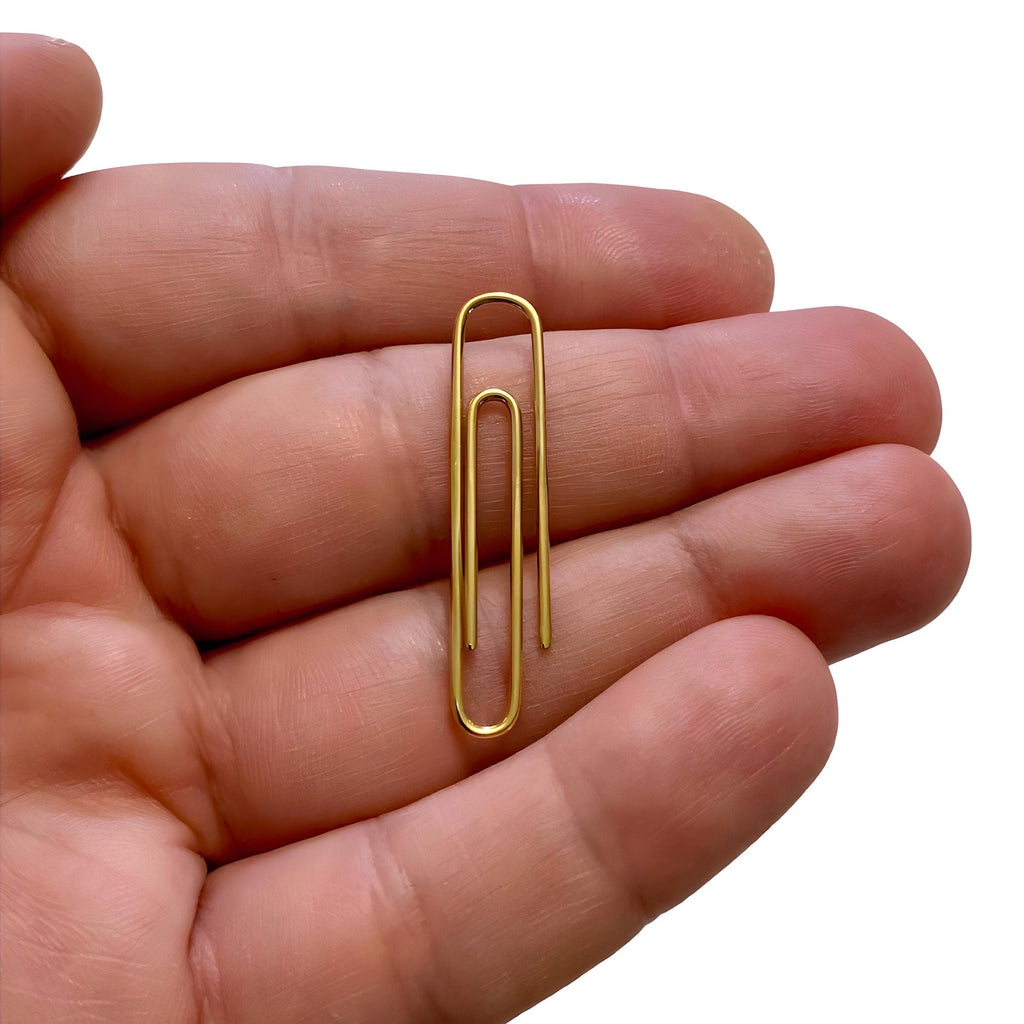 Hand holding a slim, rectangular gold money clip with smooth edges and a minimalist design.