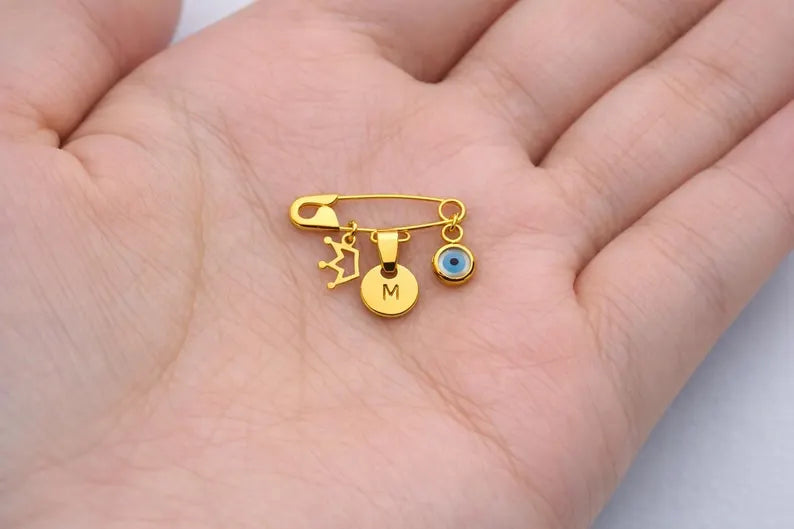 Gold Personalized Safety Baby Pin Evil Eye Brooch With Crown held in a palm - 24jewels
