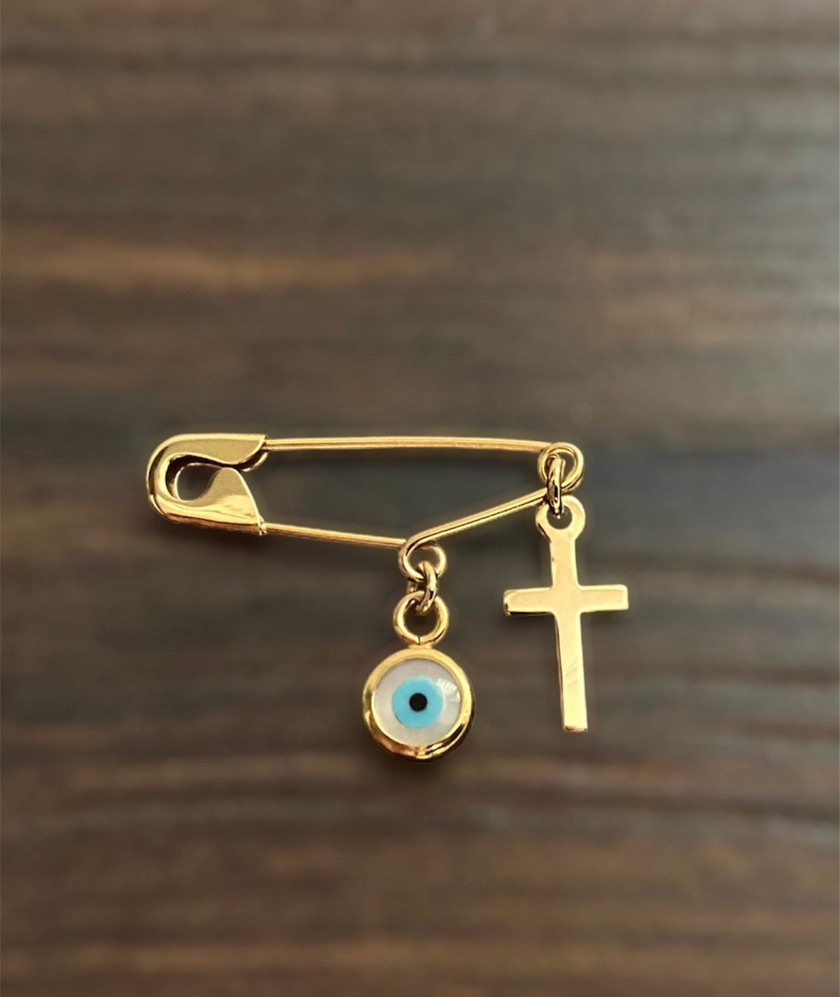 Gold Safety Pin Evil Eye Brooch with Cross on wooden surface - 24jewels