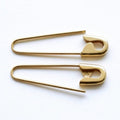 Pair of shiny gold safety pin hoop earrings with smooth curved edges on a white background.