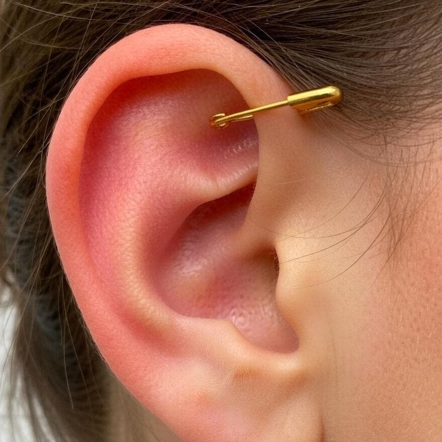 yellow gold miniature safety pin earring worn on upper ear cartilage.