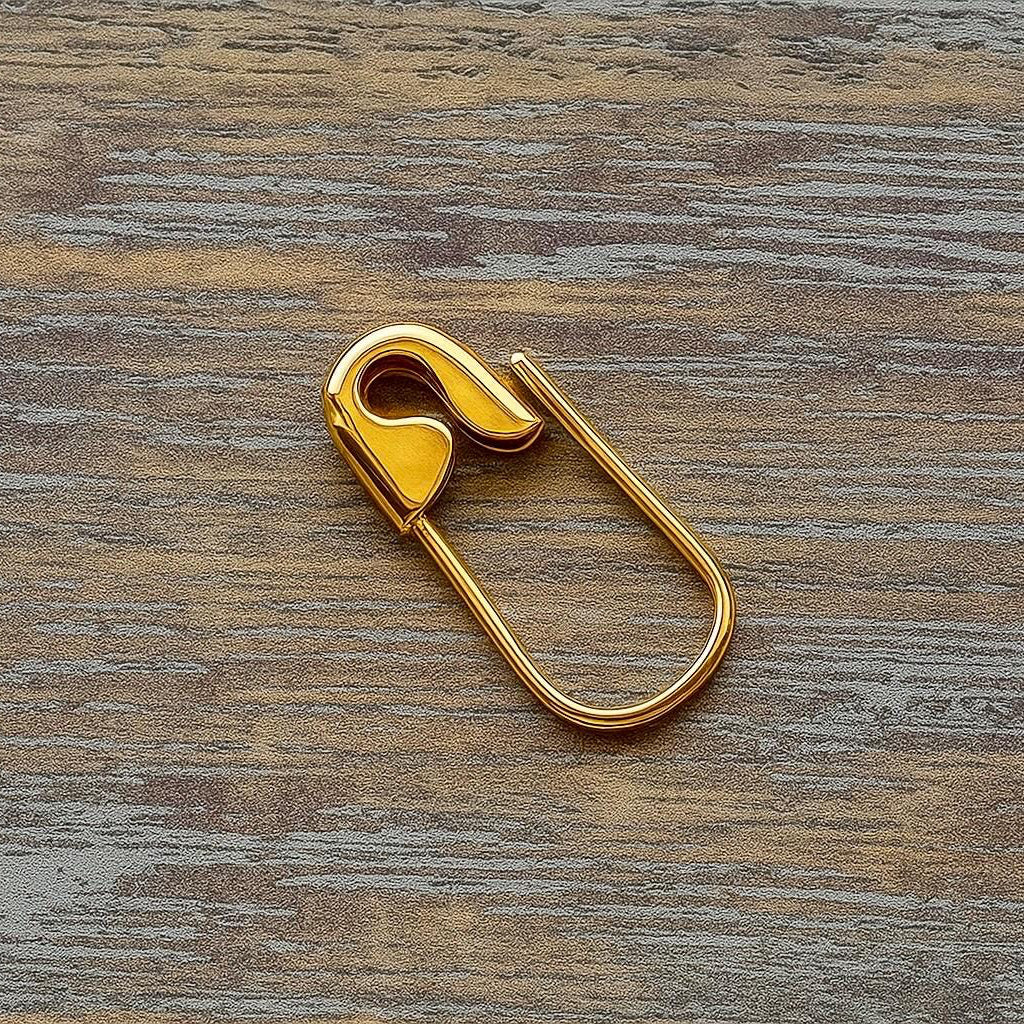 Yellow gold safety pin with smooth rounded edges on a wood surface.