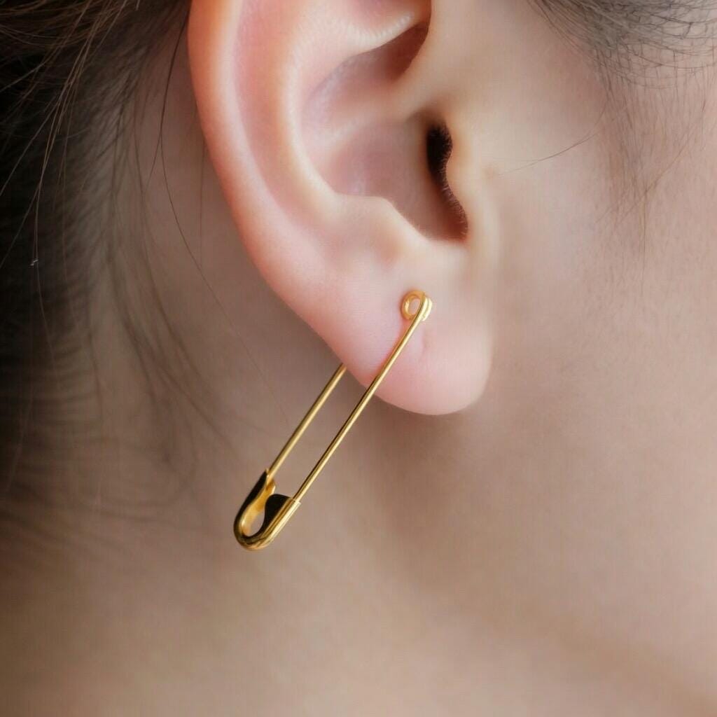 Gold safety pin silver earring measuring 1.25 inches worn in earlobe piercing.