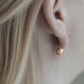 Silver gold plated safety pin earring worn on earlobe, edgy minimalist design.