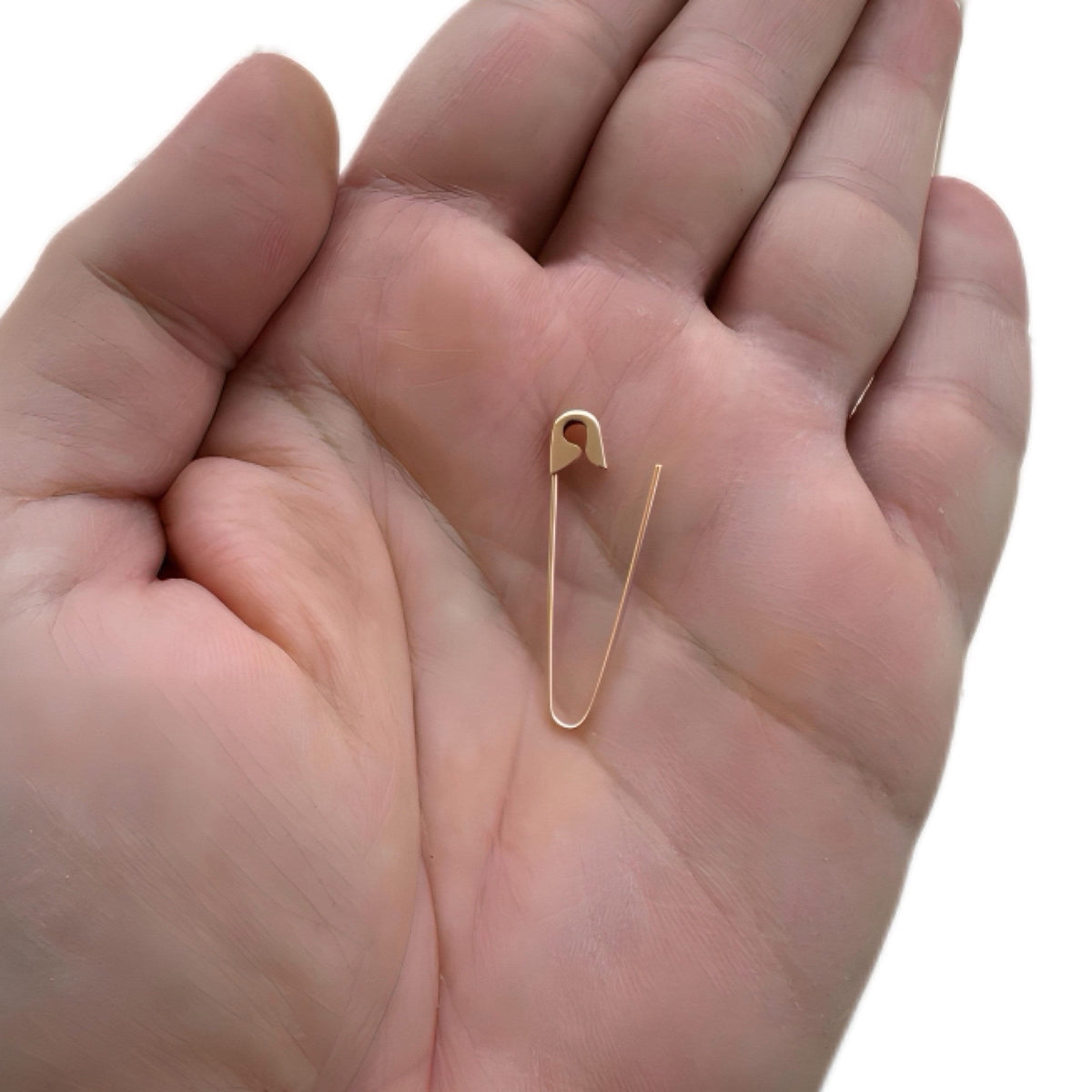 Gold plated safety pin hoop earring with 1.25-inch slim, edgy design held in hand.