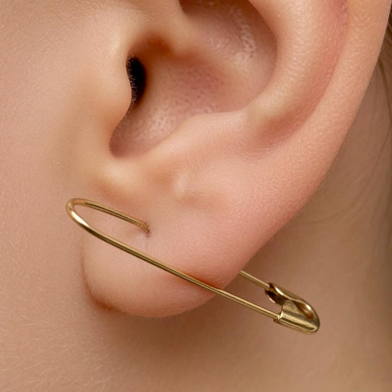 Gold plated safety pin hoop silver earring worn on ear, edgy minimalist design, 1.25 inches long.