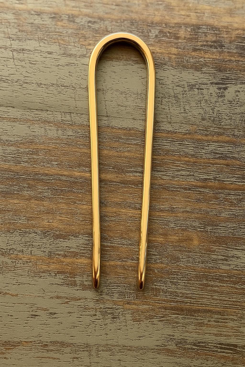Gold-tone U-shaped hair pin bun holder with smooth, polished finish on wooden surface , 3.5 inches long.