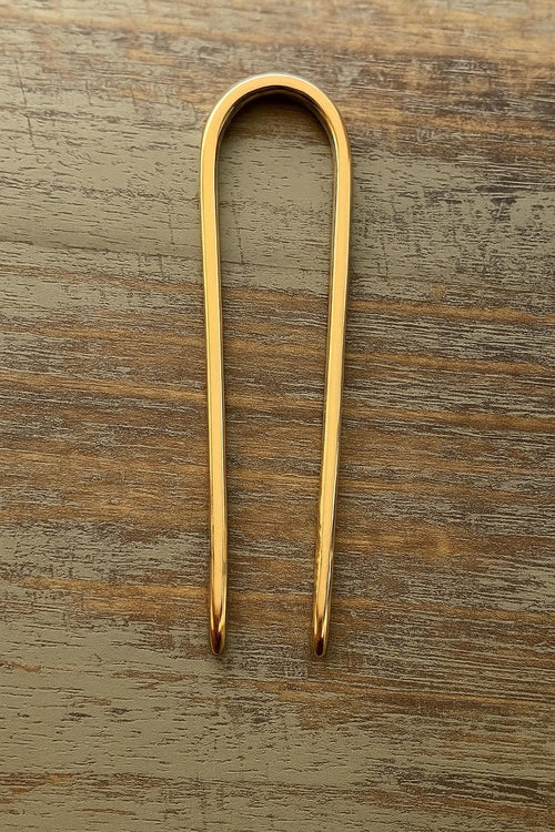 Gold-tone U-shaped hair pin bun holder with smooth, polished finish on wooden surface , 3.5 inches long.