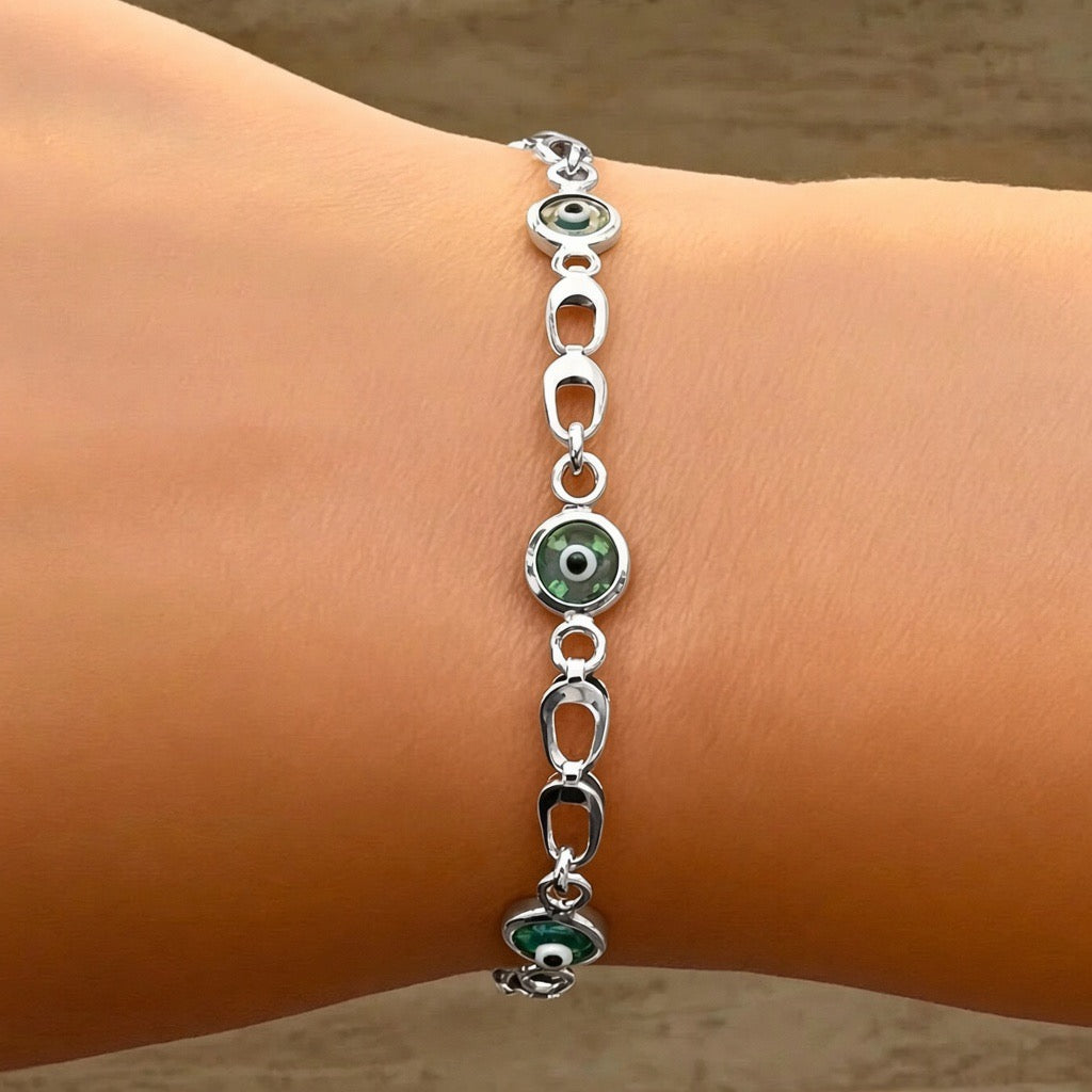 Sterling silver bracelet with gold-plated blue and white evil eye charms linked by oval and circular chain elements.