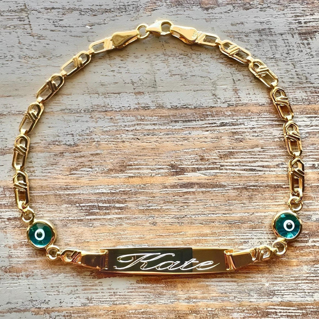 Personalized Baby Name Gold Bracelet – Nazar Protection Charms & Cursive Engraving on wooden surface - 24jewels