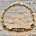 Personalized Baby Name Gold Bracelet – Nazar Protection Charms & Cursive Engraving on wooden surface - 24jewels