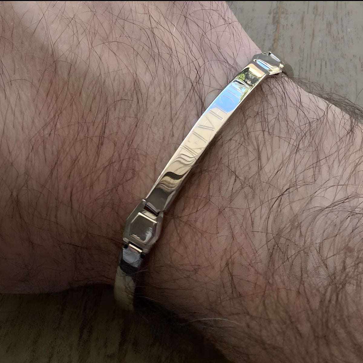 Personalized Silver Hebrew Bracelet on a man's wrist which is on a wooden surface : Men’s Wrist Band Custom Bangle Jewish Jewelry - 24jewels