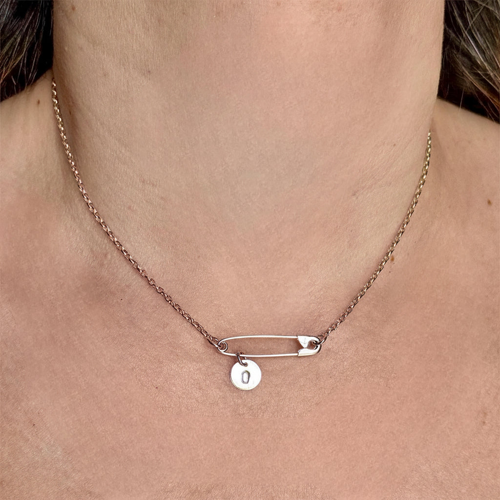 Sterling silver safety pin necklace with round initial "J" charm on delicate chain.