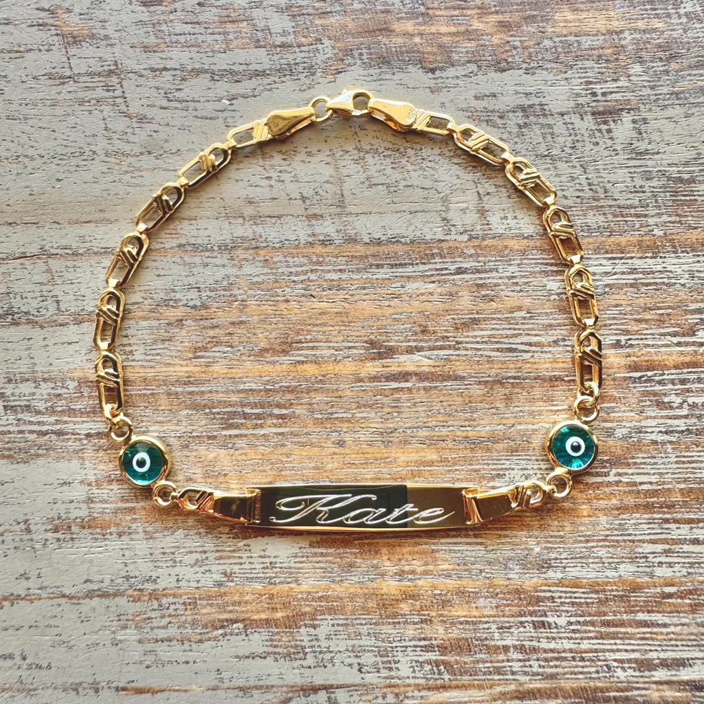 Personalized Baby Name Gold Bracelet – Nazar Protection Charms & Cursive Engraving on wooden surface - 24jewels