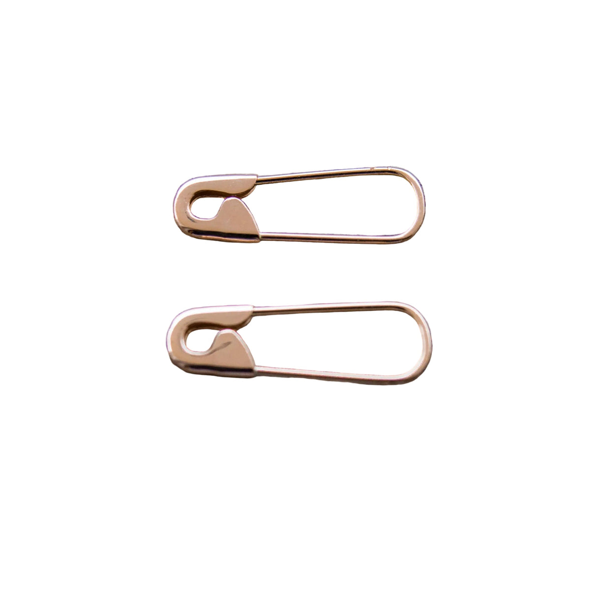Pair of small rose gold-tone hoop earrings designed as safety pins with a polished finish on white background .
