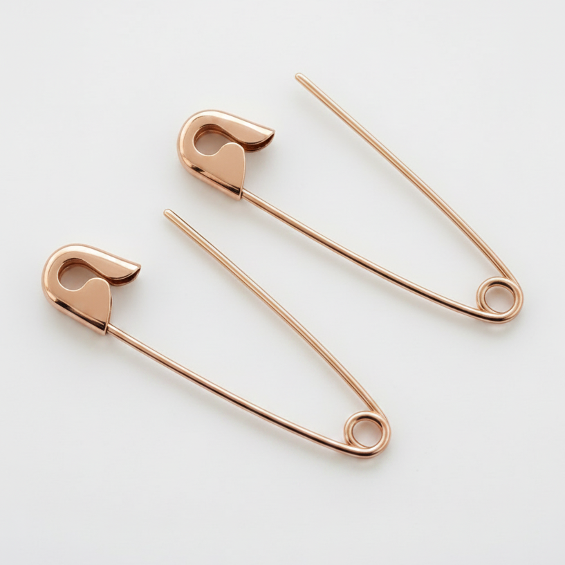 Rose gold safety pin silver earrings with a sleek, polished finish, 1.25 inches long on white background .