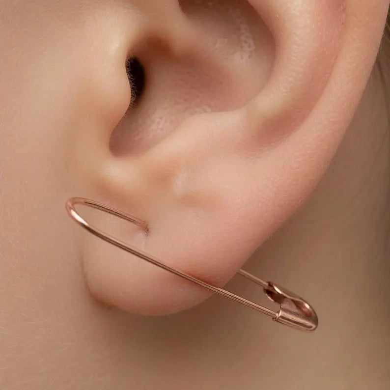 Rose gold plated safety pin hoop earring, 1.25 inches, worn on ear.