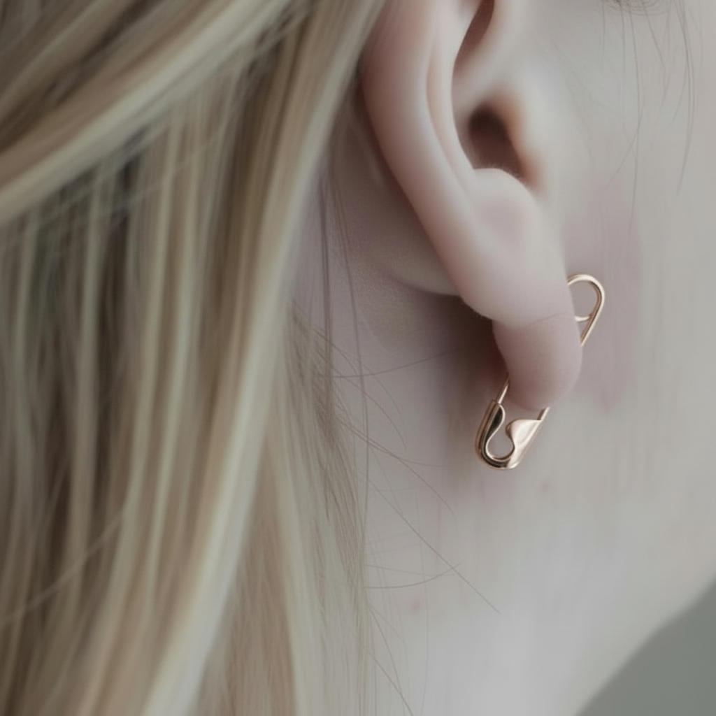 Rose gold safety pin earring with sleek, minimalist edgy design worn on earlobe.