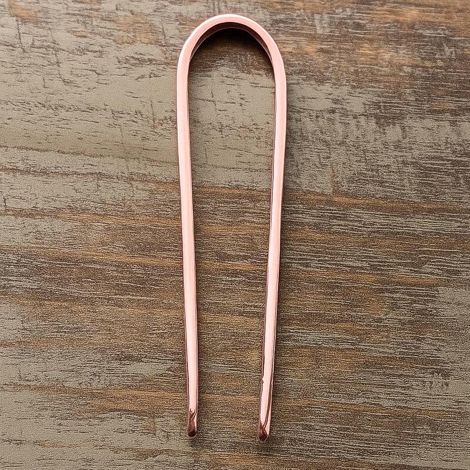 Rose Gold metal U-shaped hair pin with rounded ends, 3.5 inches long, sleek minimal design on wooden surface .