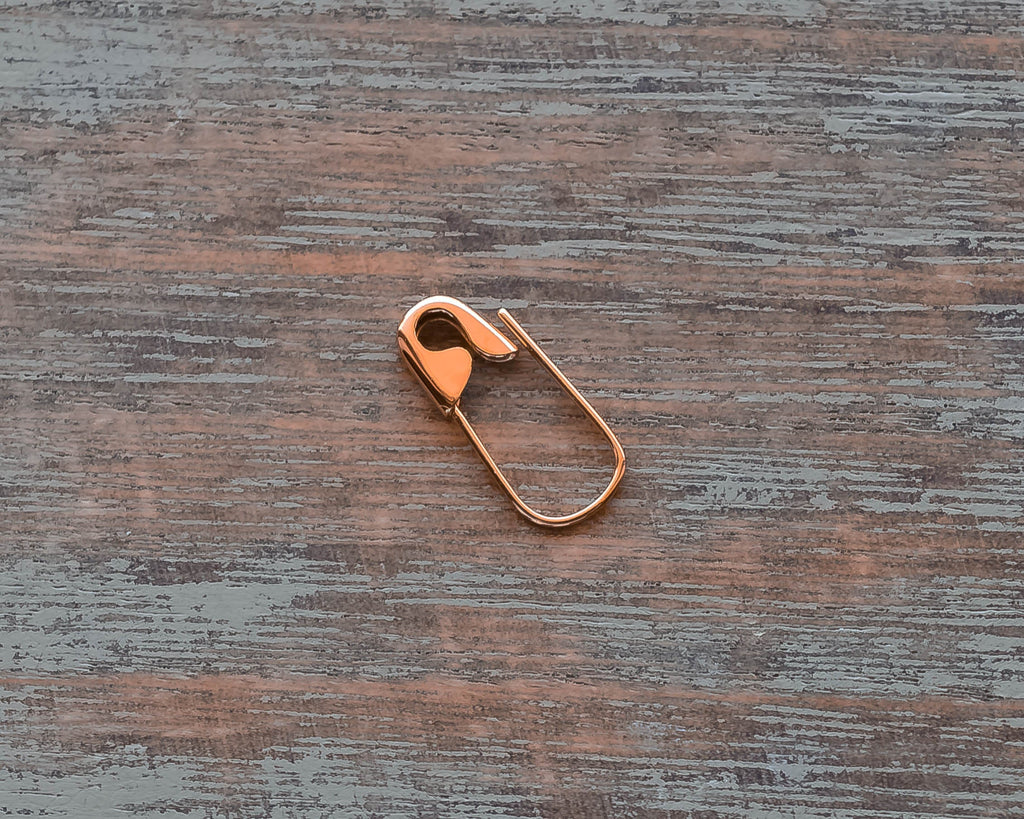 Rose Gold-tone mini hoop earring shaped like a safety pin with a shiny finish.