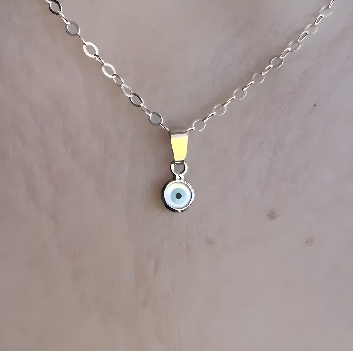 Sterling silver necklace with a small round evil eye pendant on a delicate chain.