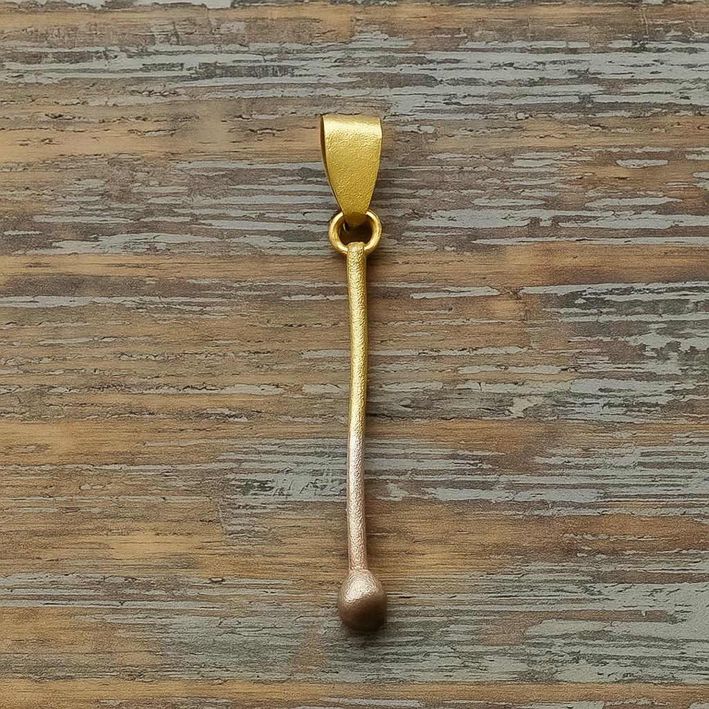 Gold plated sterling silver pendant shaped like a minimalist matchstick on wooden background.