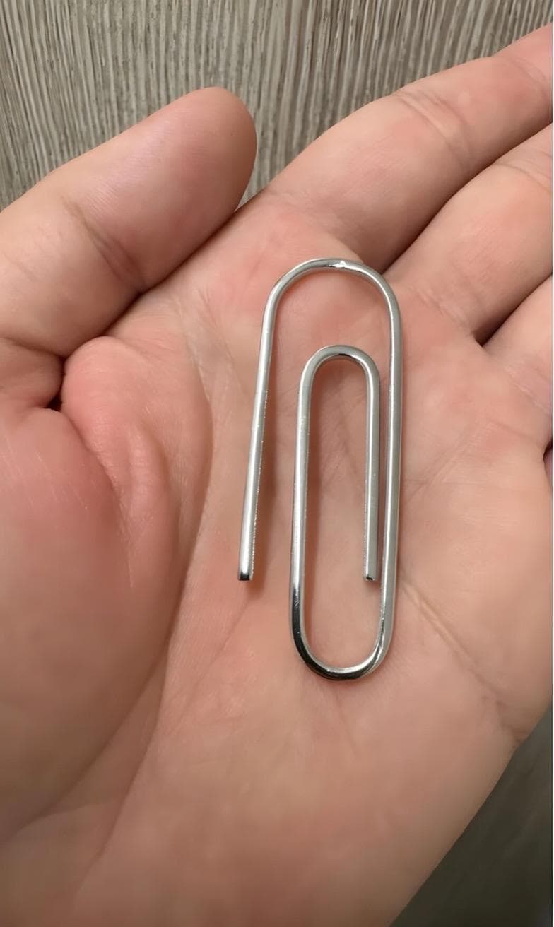 Sterling silver paperclip money clip with smooth, polished finish held in hand.
