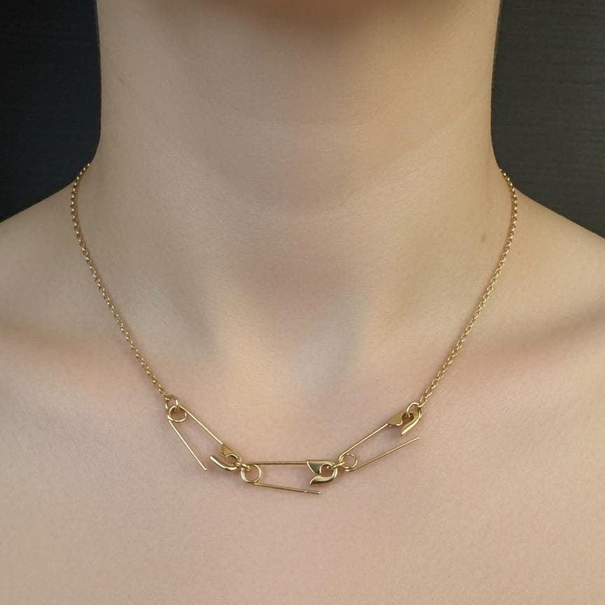 Gold-plated necklace with three delicate safety pin charms linked on a fine chain.