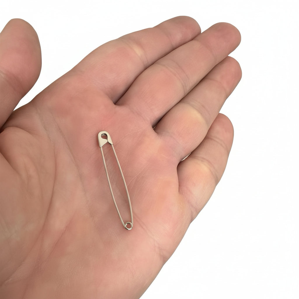 Sterling silver safety pin earring with a delicate wire frame measuring 1.75 inches, resting on an open palm.