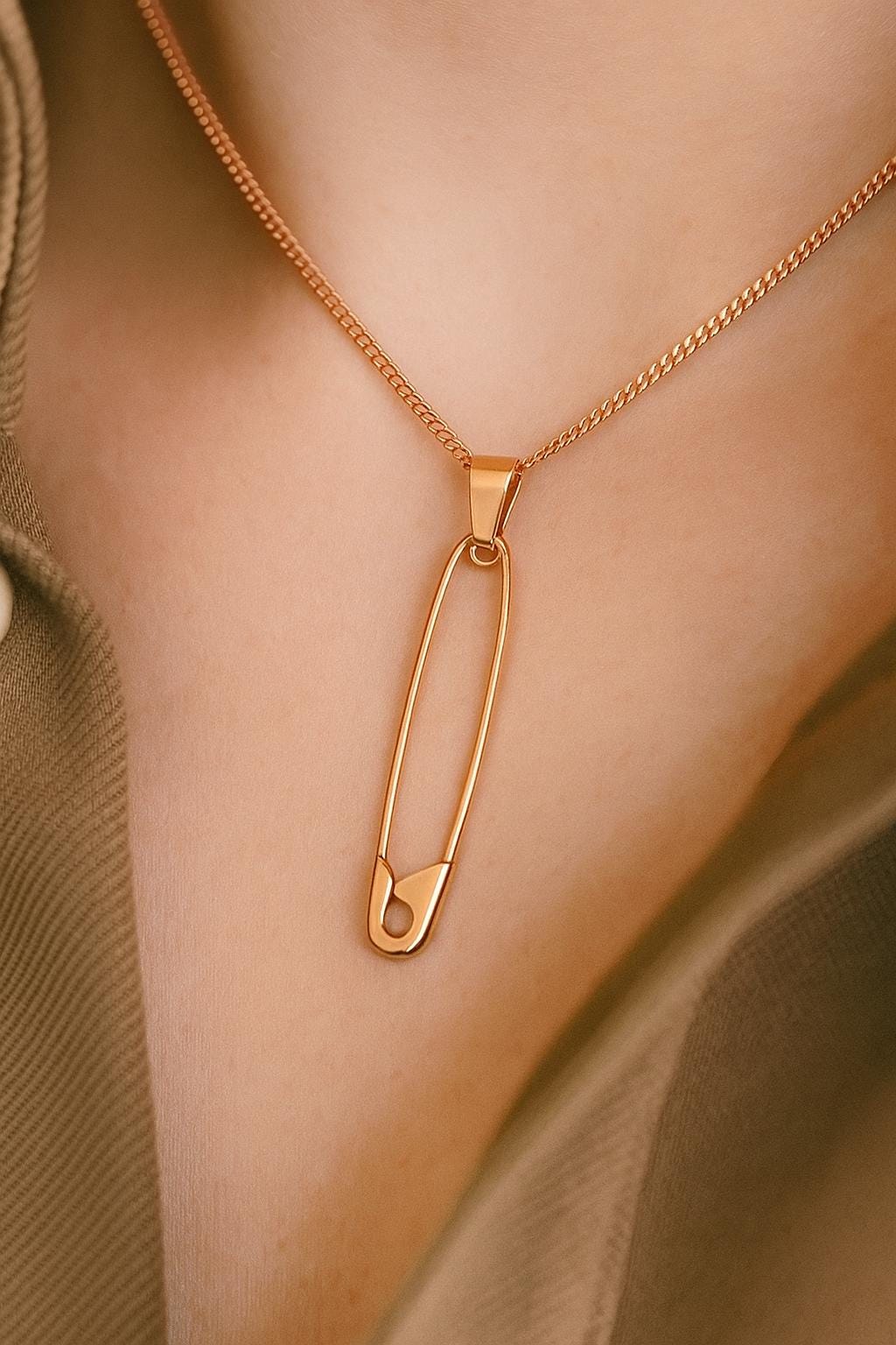 Sterling silver rose gold plated safety pin pendant on a delicate chain necklace against skin.