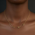 Gold plated safety pin charm holder necklace with delicate chain on model's neck.