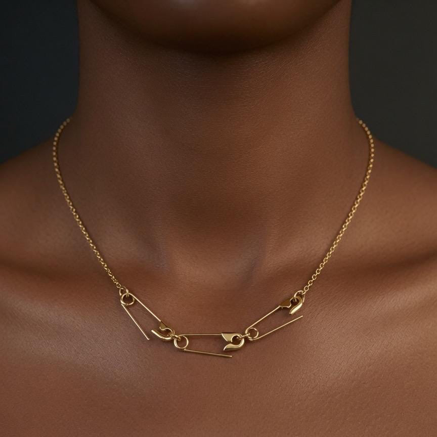 Gold plated safety pin charm holder necklace with delicate chain on model's neck.