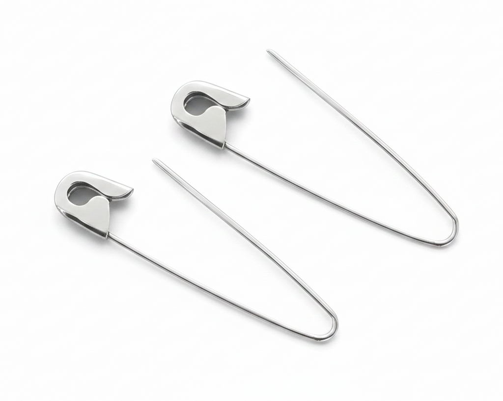 Sterling silver safety pin hoop earrings with 1.25-inch thin wire and sleek polished finish on white background .