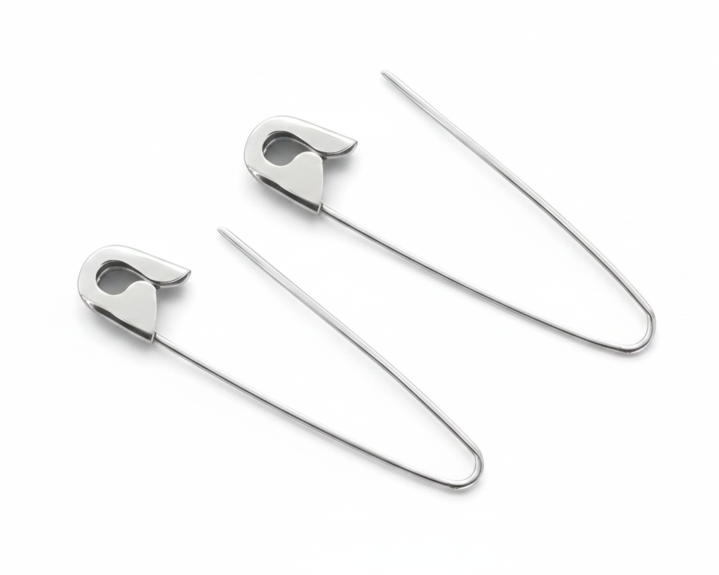 Sterling silver safety pin hoop earrings with 1.25-inch thin wire and sleek polished finish on white background .