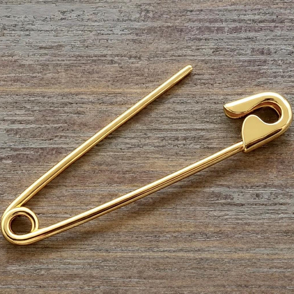 Gold plated safety pin silver earring 1.3” with 16 gauge thick wire on wood background.