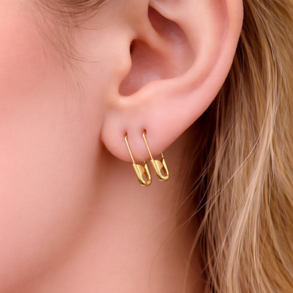 Sterling silver mini safety pin gold Plated earrings worn on earlobe with smooth, shiny finish.
