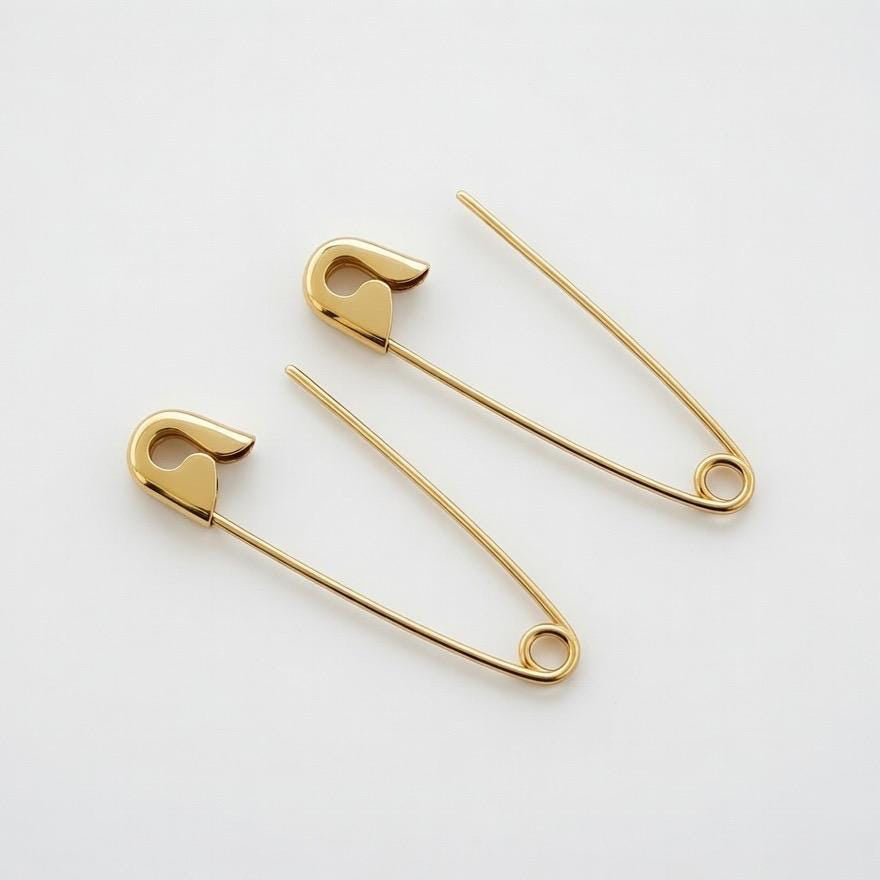 Gold plated safety pin earrings with minimalist industrial design, 1.25 inches long on white background .