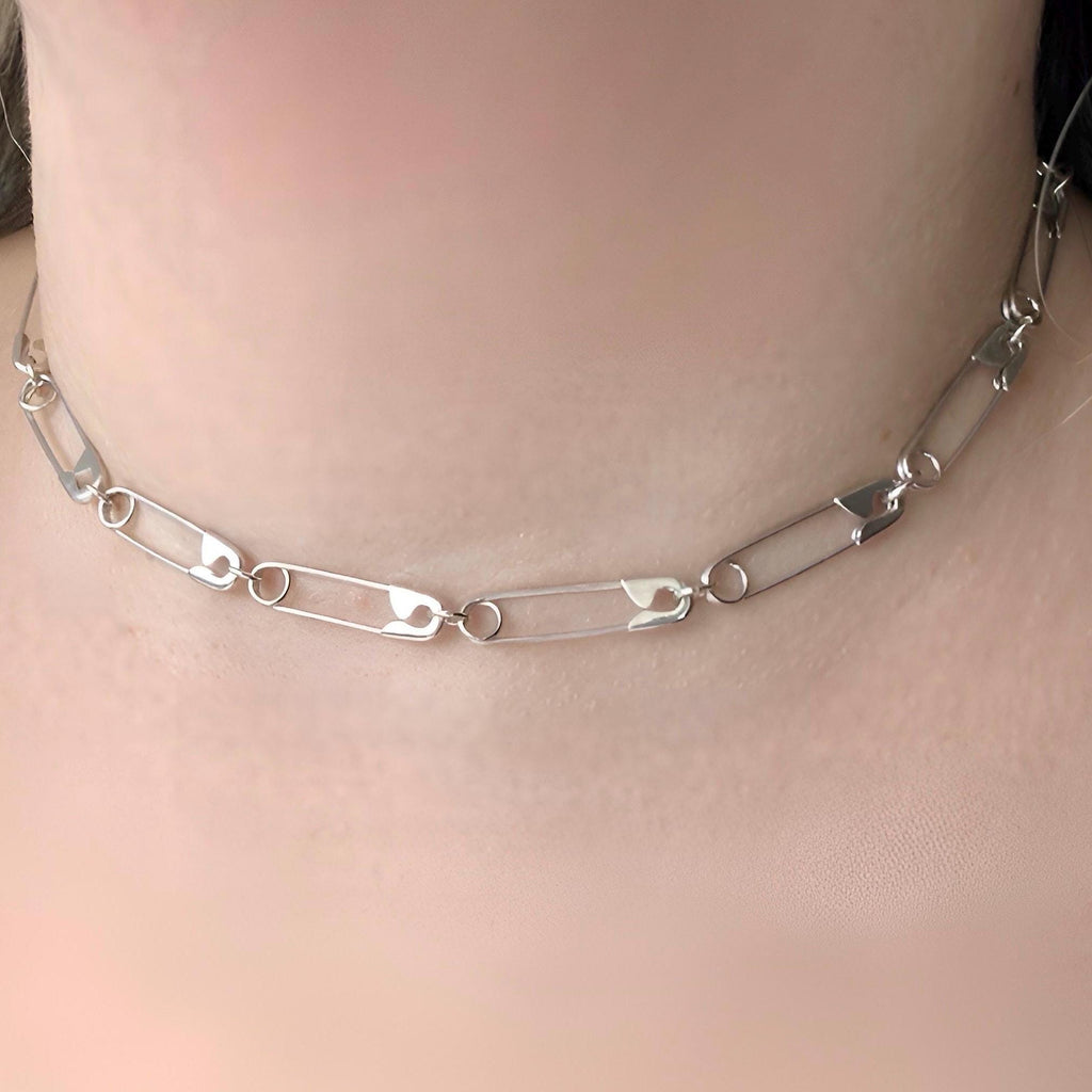 Sterling silver safety pin chain necklace with alternating open and closed links, worn as a choker.