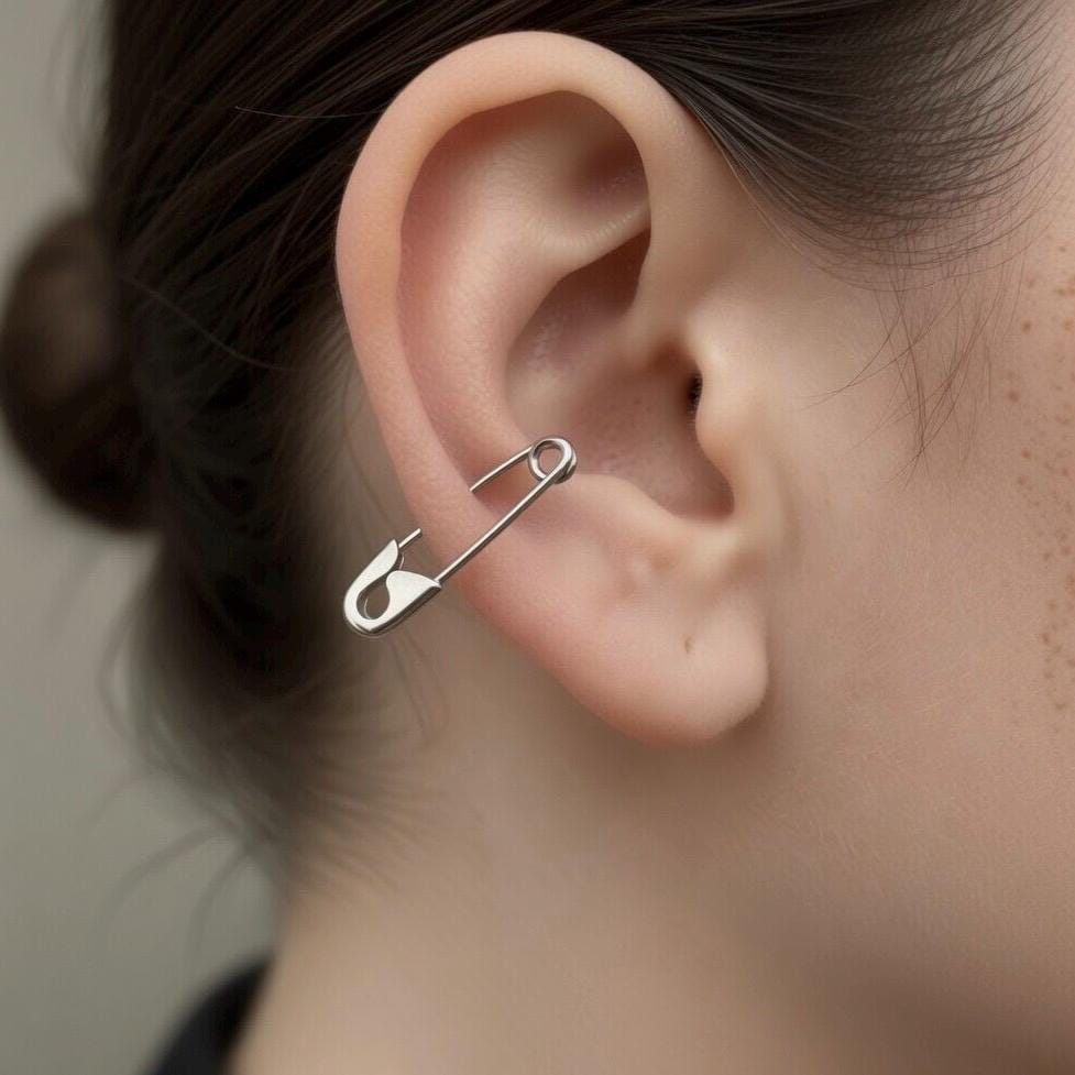 Sterling silver safety pin earring with a shiny finish, worn on the ear's helix.