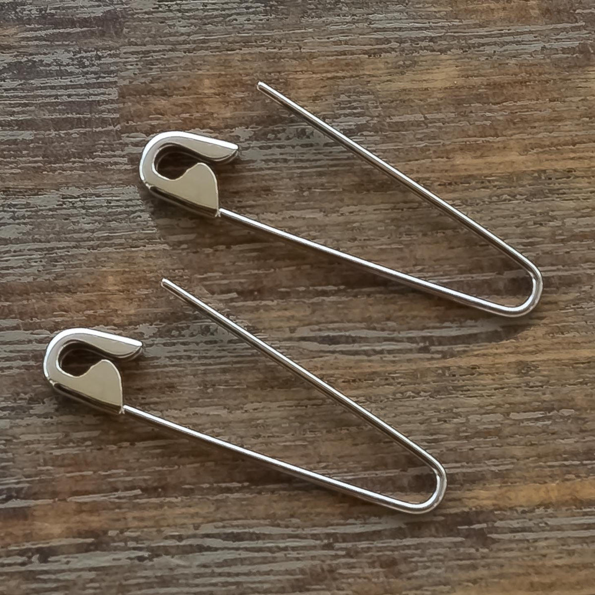White Gold hoop earrings shaped like oversized safety pins with a shiny finish.