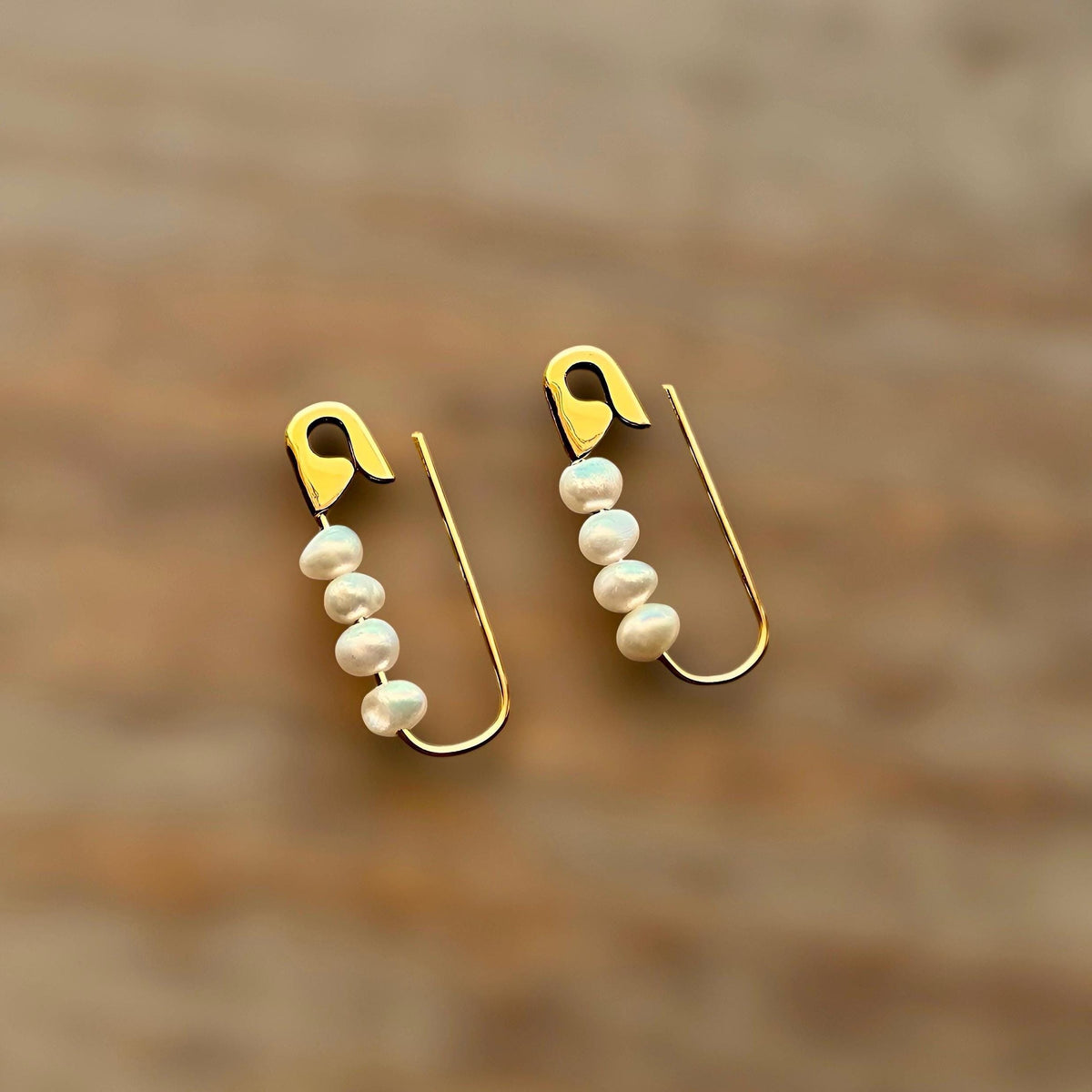 Gold safety pin earrings with four white freshwater pearls on each hoop, 3/4 inch length.