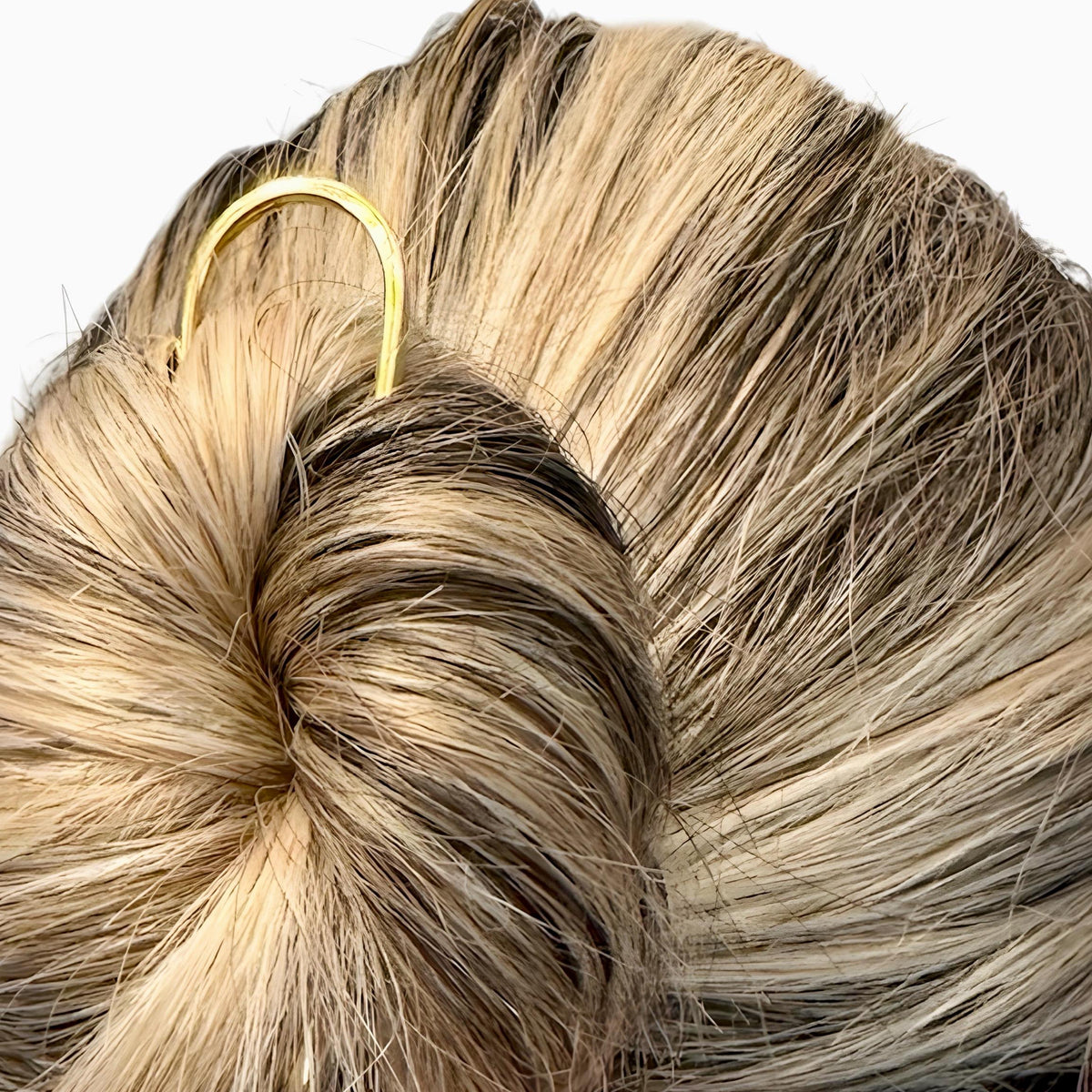 Gold U-shaped metal hair pin securing a twisted bun in blonde hair.