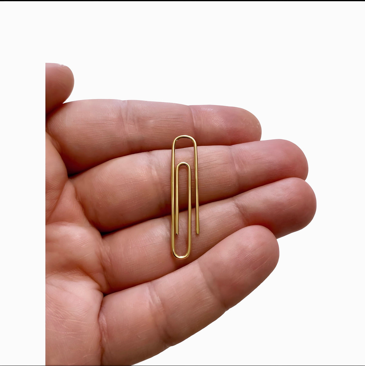 Gold plated shiny paperclip money clip held in palm with smooth finish.